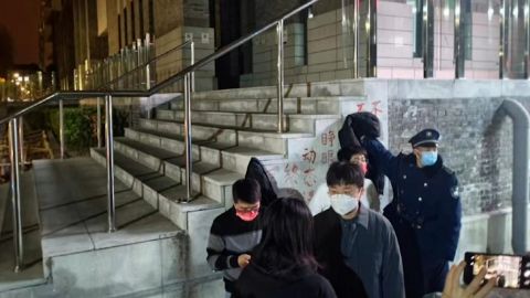 Bir güvenlik görevlisi, Pekin'deki Pekin Üniversitesi kampüsünde Sıfır Covid'e karşı bir protesto pankartını kapatmaya çalışıyor.